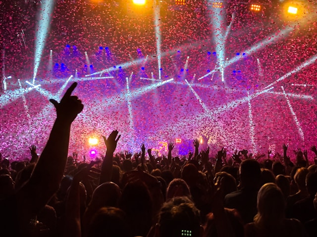 eventi estivi pubblico ad un concerto con le mani alzate, giochi di luci e coriandoli